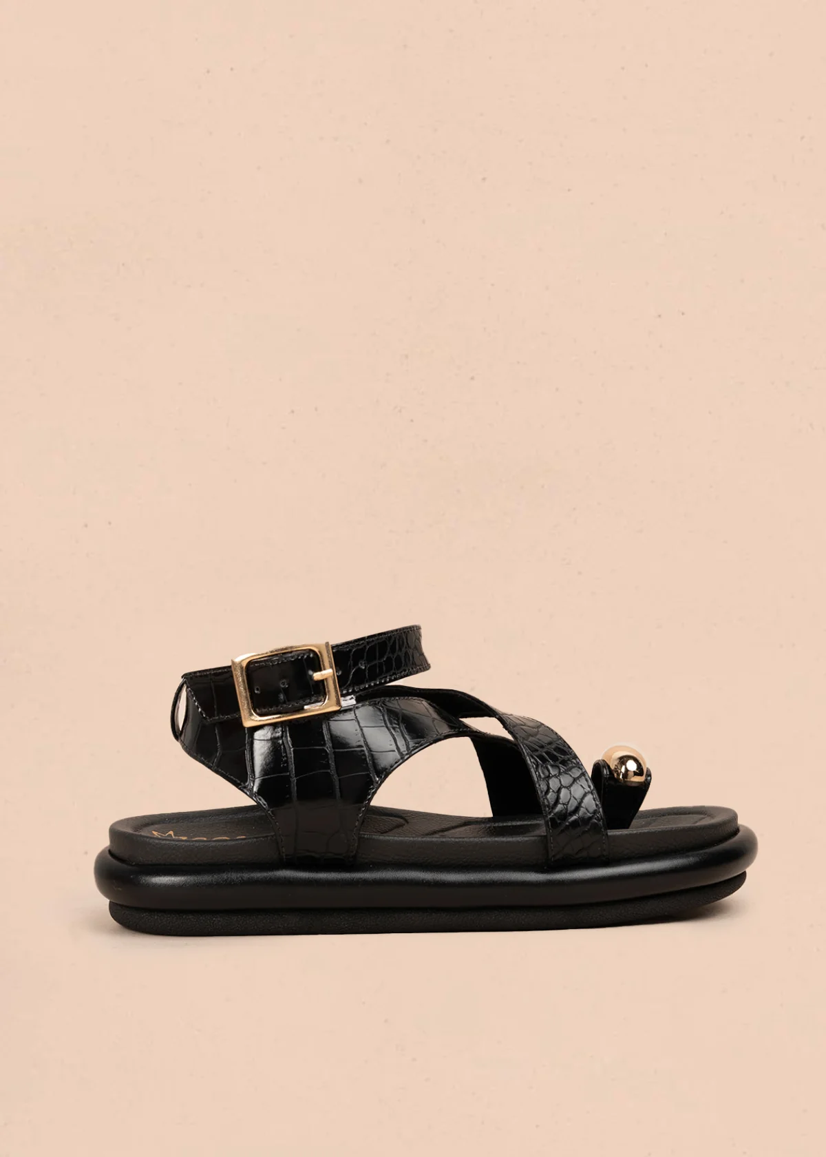 Sandalia plana color negro con correas cruzadas y detalle metálico dorado 106957
